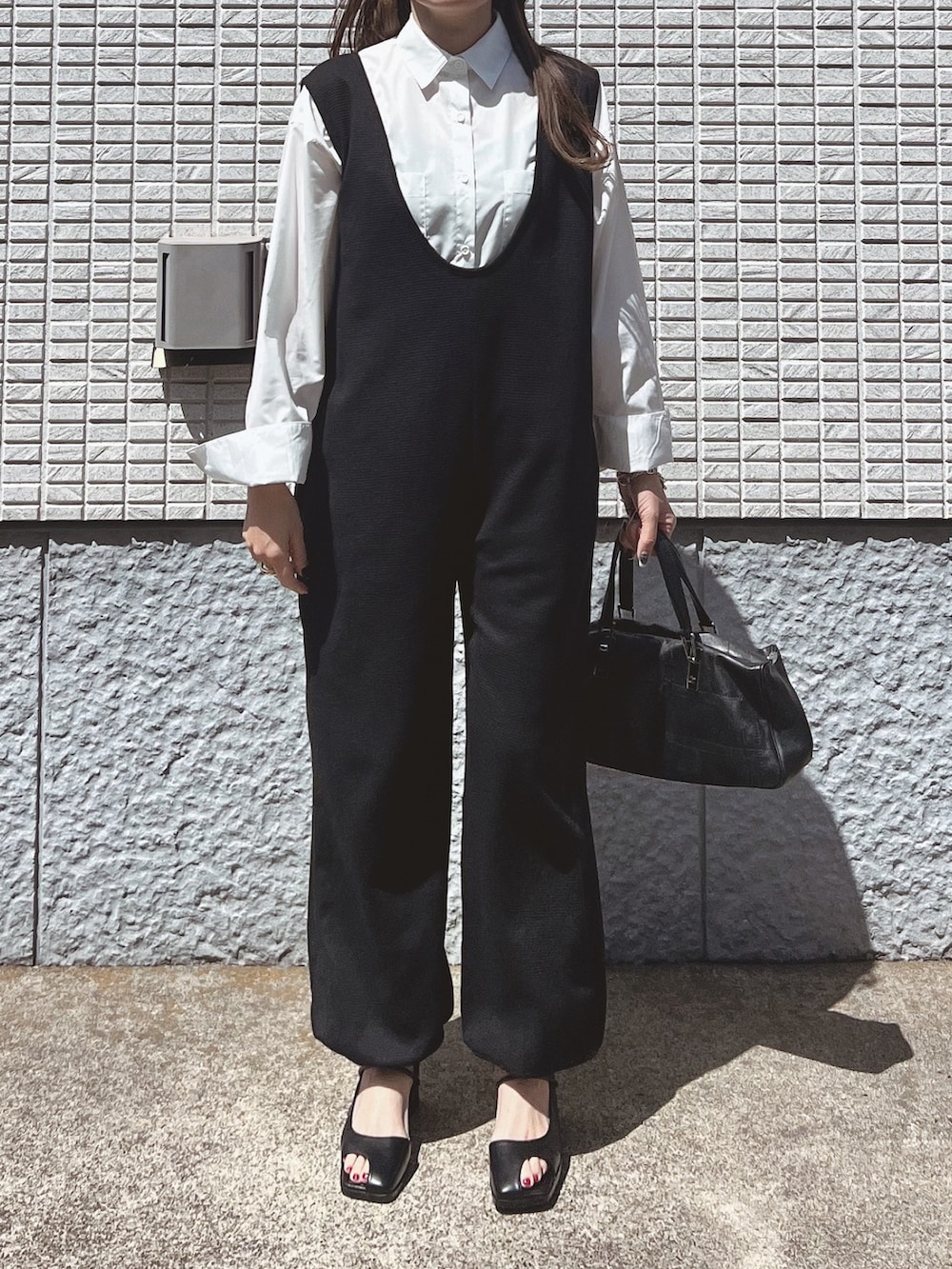 ブラック系のサロペット/オーバーオール、ホワイト系のシャツ/ブラウス、ブラック系のバッグを着用したレディースの春コーディネートの3枚目の写真