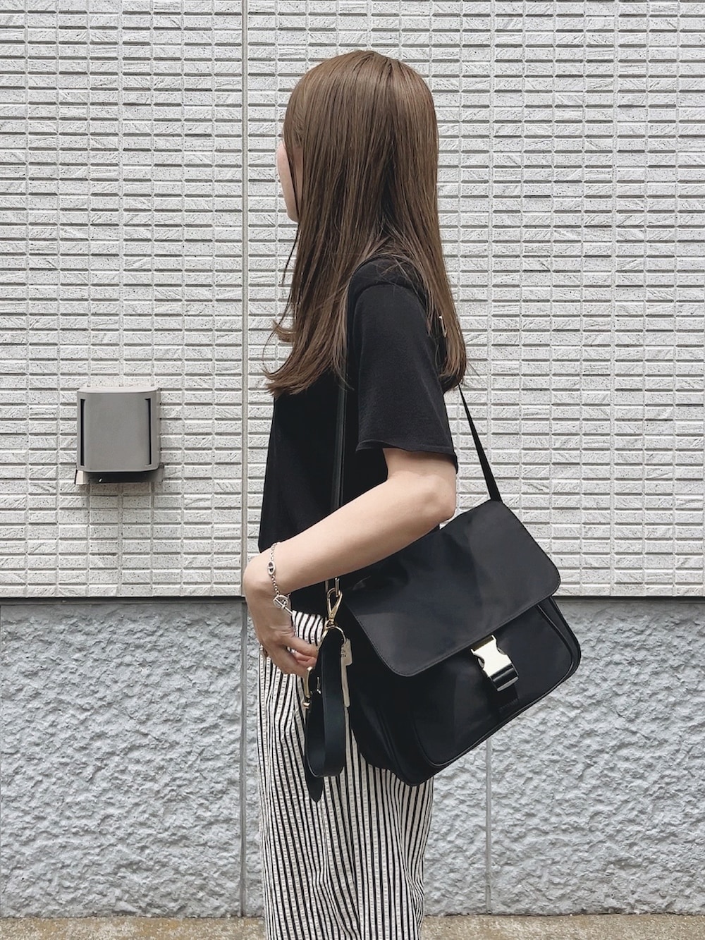 ブラック系のバッグ、ブラック系のポロシャツ、ホワイト系のスニーカーを着用したレディースの春コーディネートの3枚目の写真