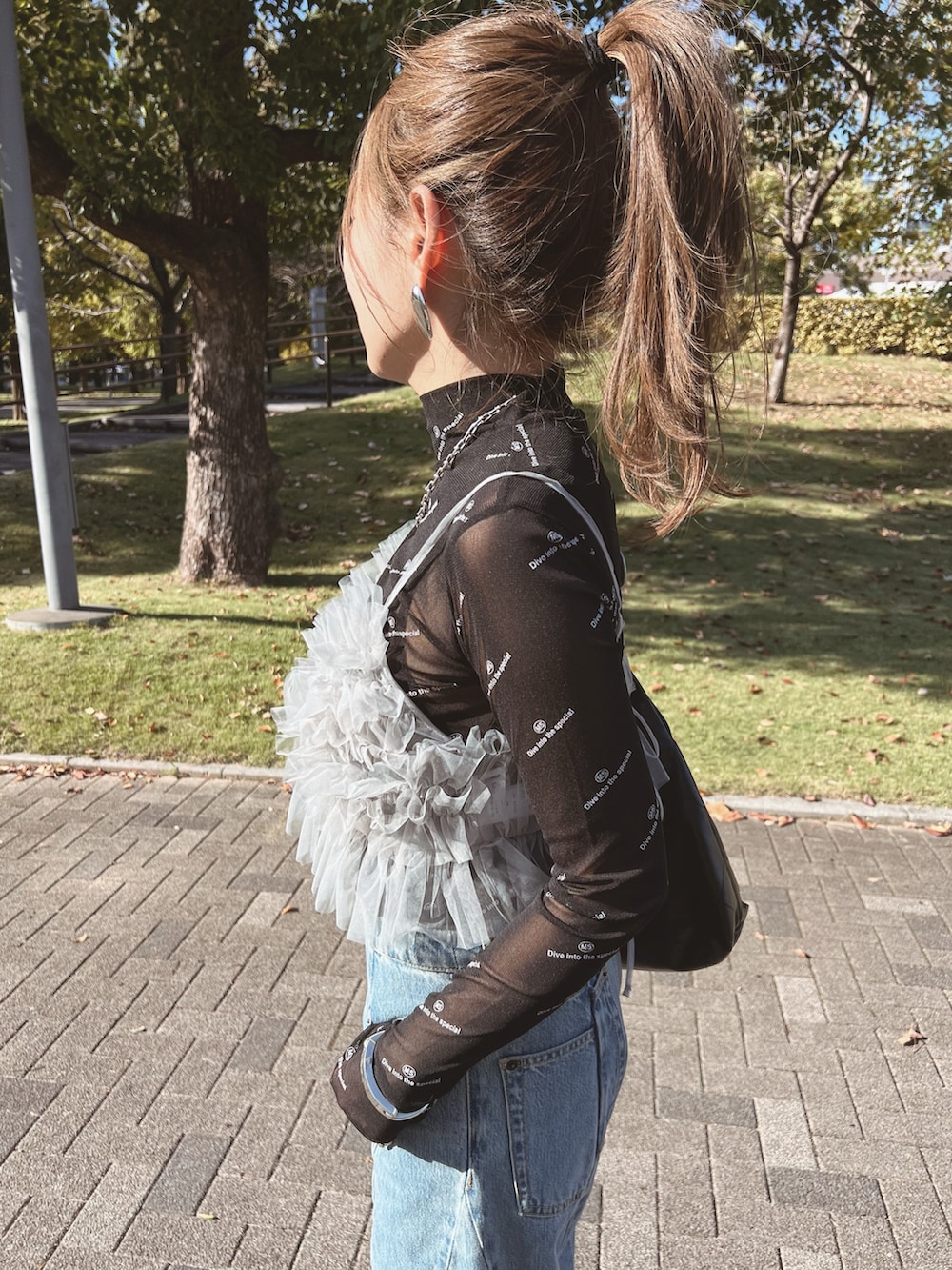 グレー系のキャミソール、ブラック系のTシャツ/カットソー、ブルー系のデニムパンツを着用したレディースの秋コーディネートの5枚目の写真