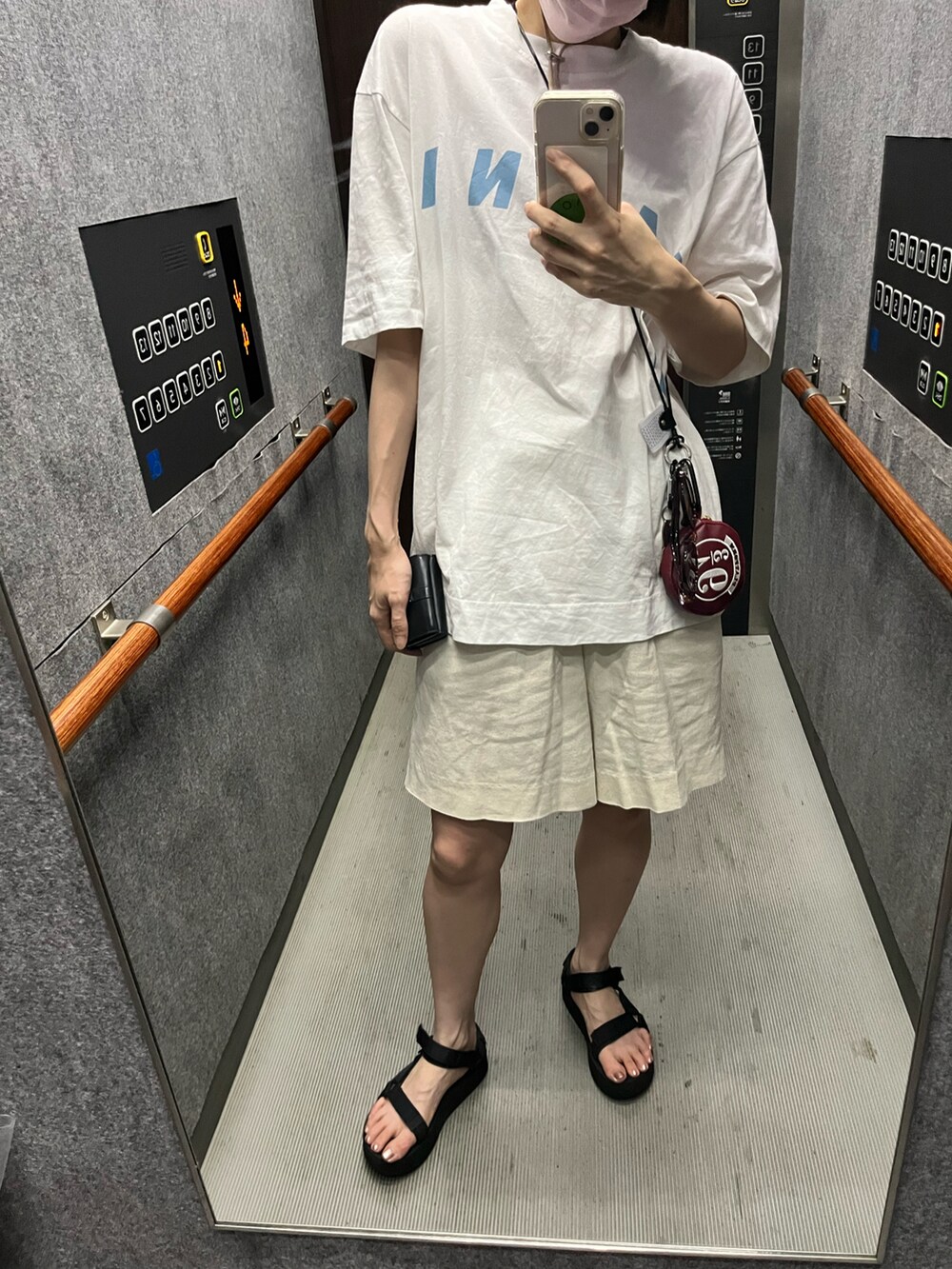 ブラック系のサンダル、ホワイト系のTシャツ/カットソー、ブラック系の財布を着用したレディースの夏コーディネートの2枚目の写真