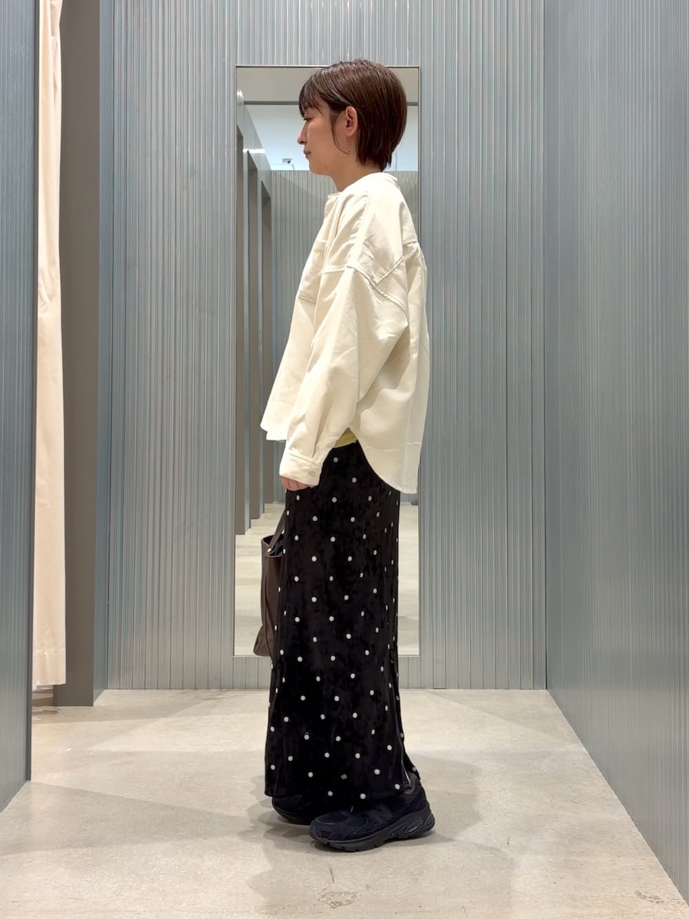 イエロー系のTシャツ/カットソー、ホワイト系のシャツ/ブラウス、ブラック系のスカートを着用したレディースの秋コーディネートの2枚目の写真