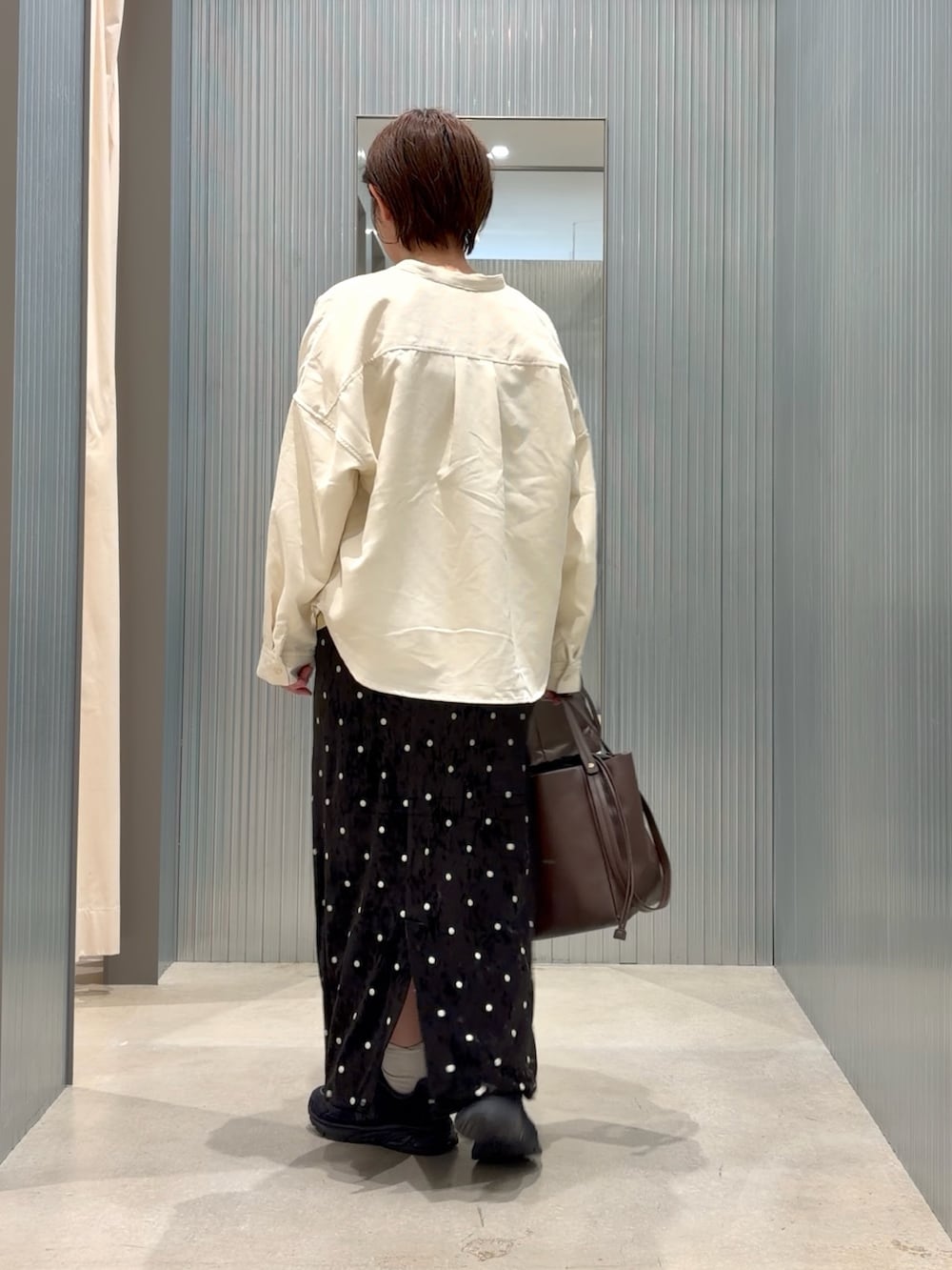 イエロー系のTシャツ/カットソー、ホワイト系のシャツ/ブラウス、ブラック系のスカートを着用したレディースの秋コーディネートの3枚目の写真
