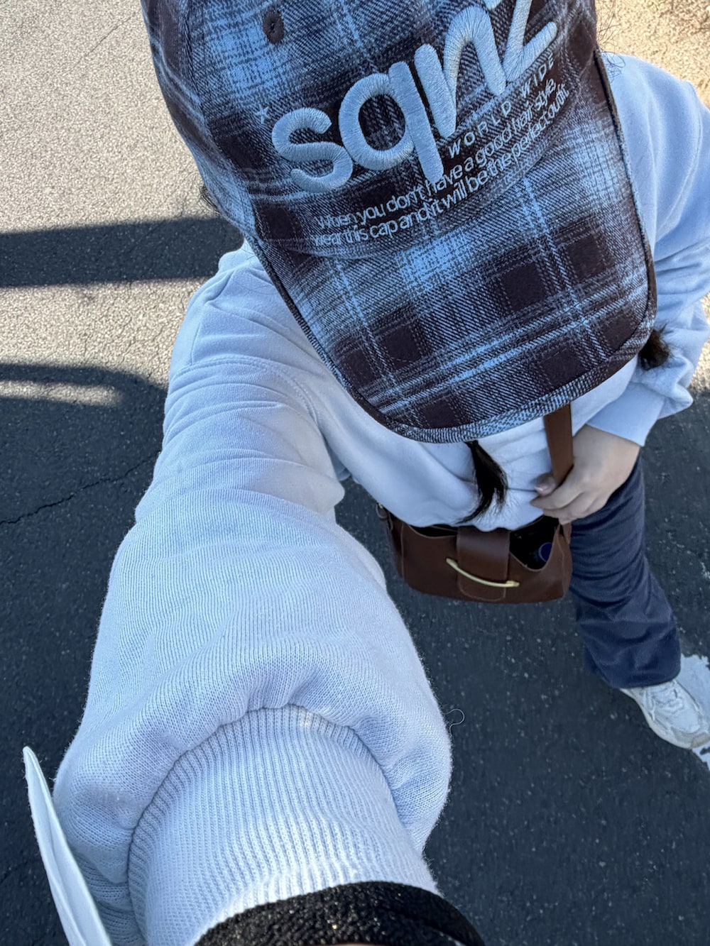 ブルー系のスウェット、ブラウン系のショルダーバッグ、ホワイト系のスニーカーを着用したレディースの秋コーディネートの2枚目の写真