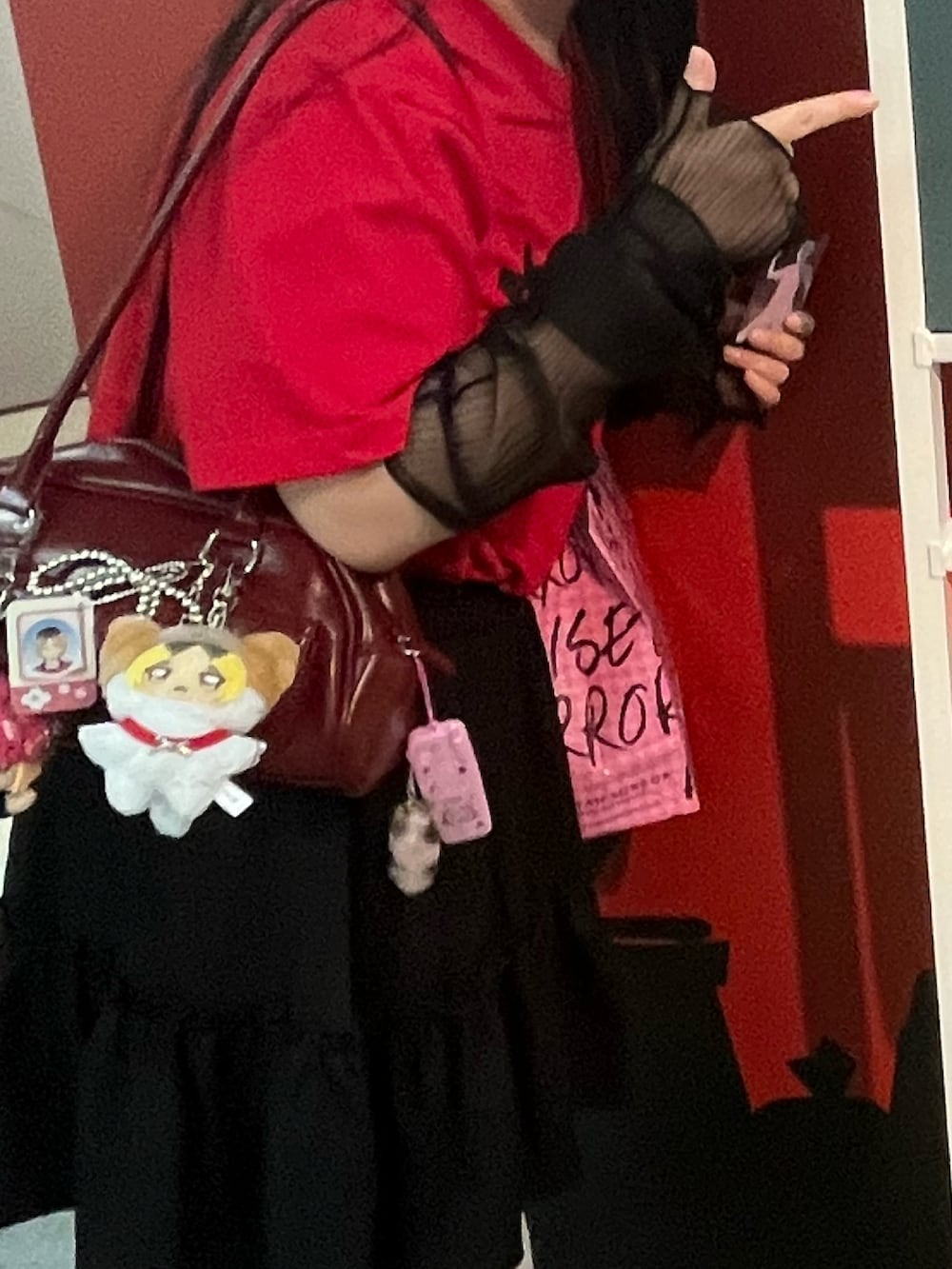 ブラック系のスニーカー、ブラック系のスカート、レッド系のTシャツ/カットソーを着用したレディースの秋コーディネートの2枚目の写真