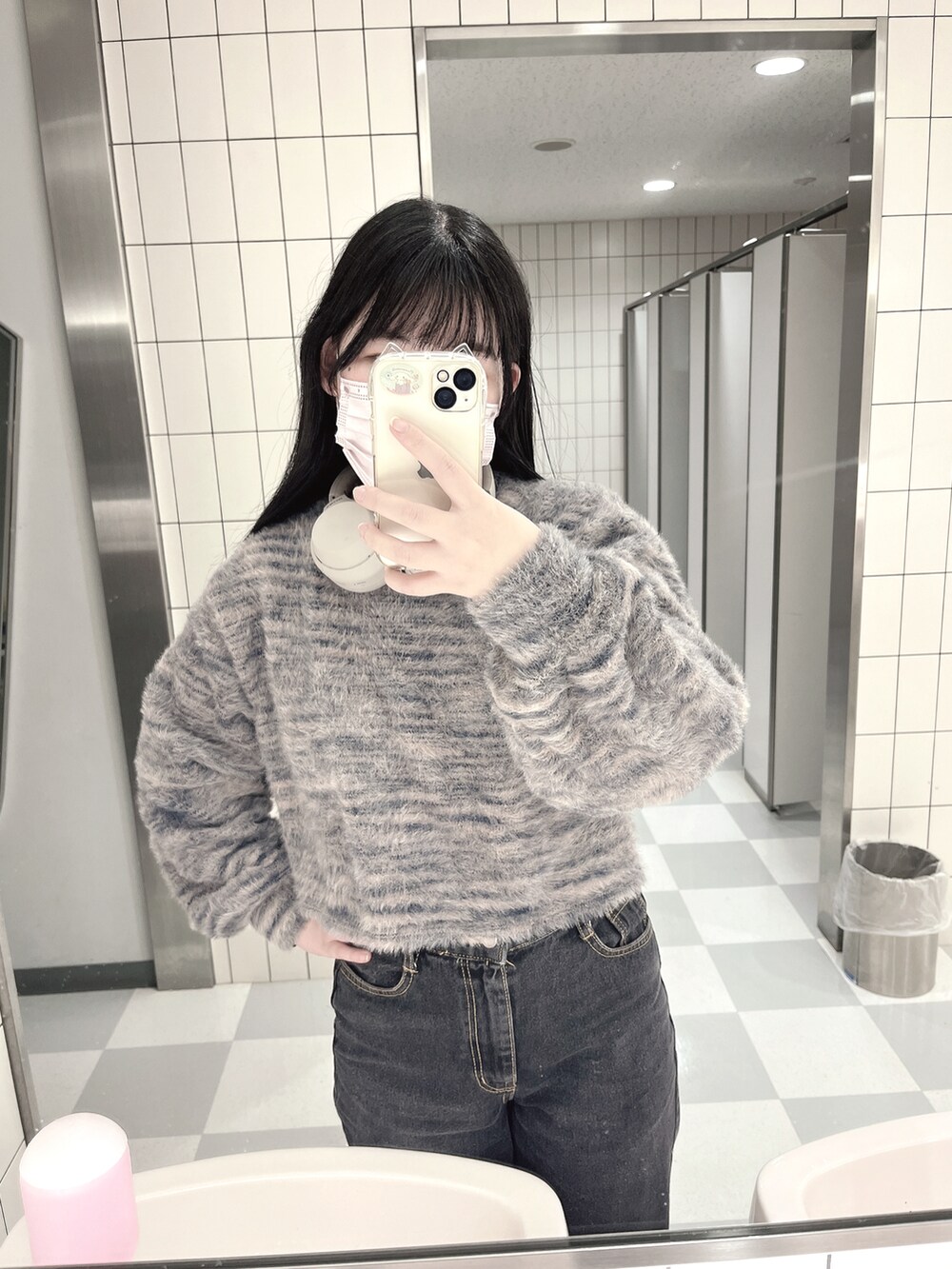 ブラック系のデニムパンツ、ブラック系のニット/セーター、ホワイト系のスニーカーを着用したレディースの冬コーディネートの2枚目の写真