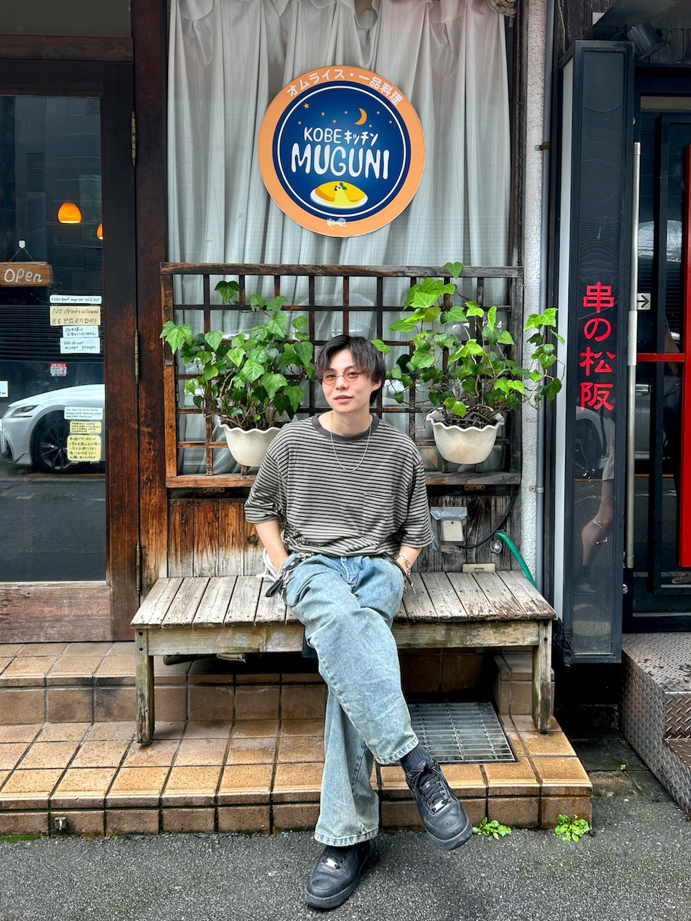 ブルー系のデニムパンツ、ブラック系のスニーカー、グリーン系のTシャツ/カットソーを着用したメンズの夏コーディネートの2枚目の写真