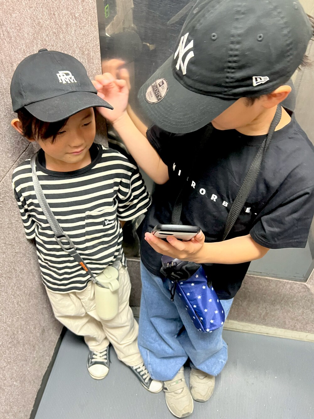 ブラック系のキャップを着用したキッズの春コーディネートの2枚目の写真