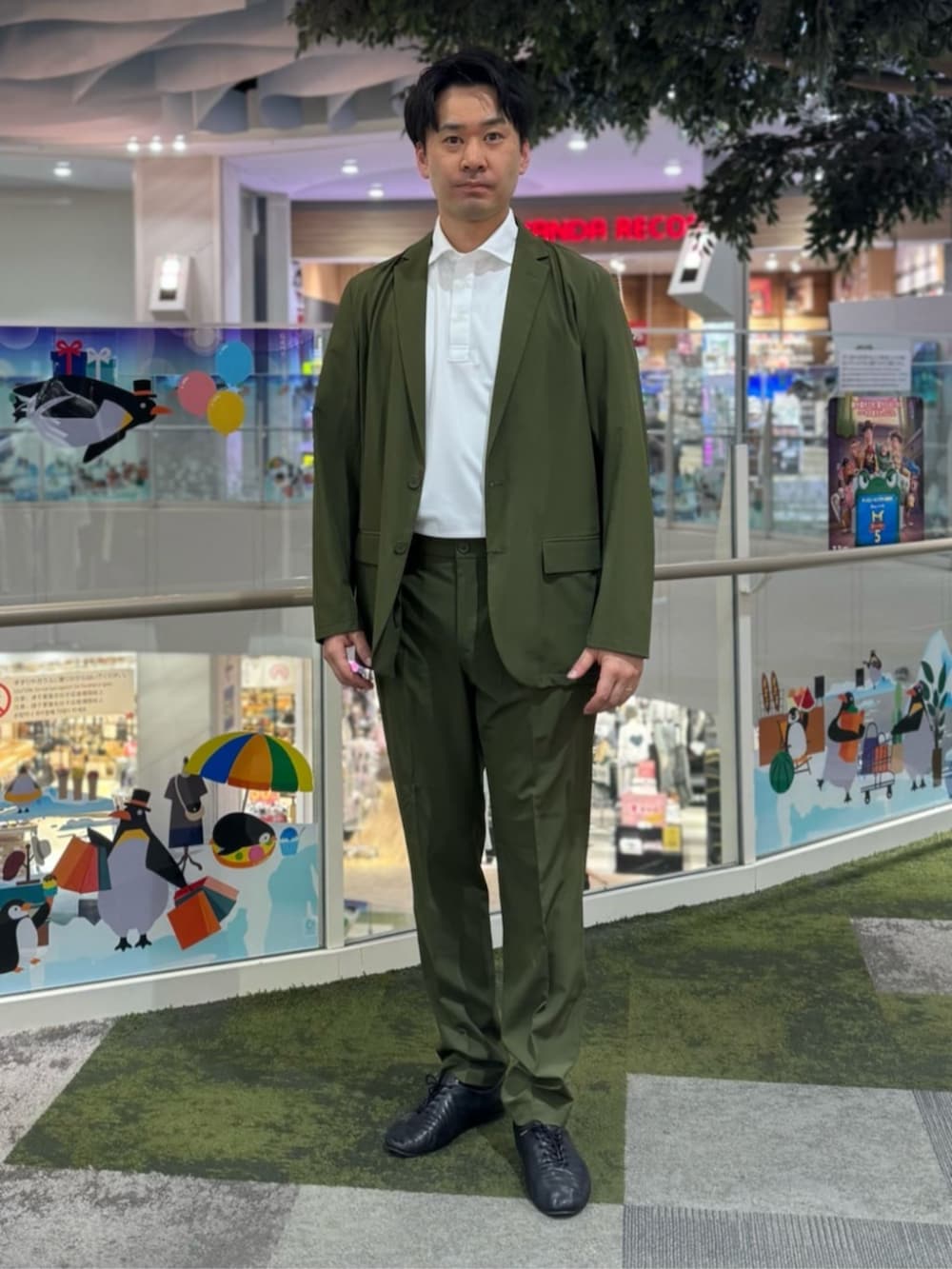 グリーン系のスーツセット、ホワイト系のポロシャツを着用したメンズの夏コーディネートの7枚目の写真