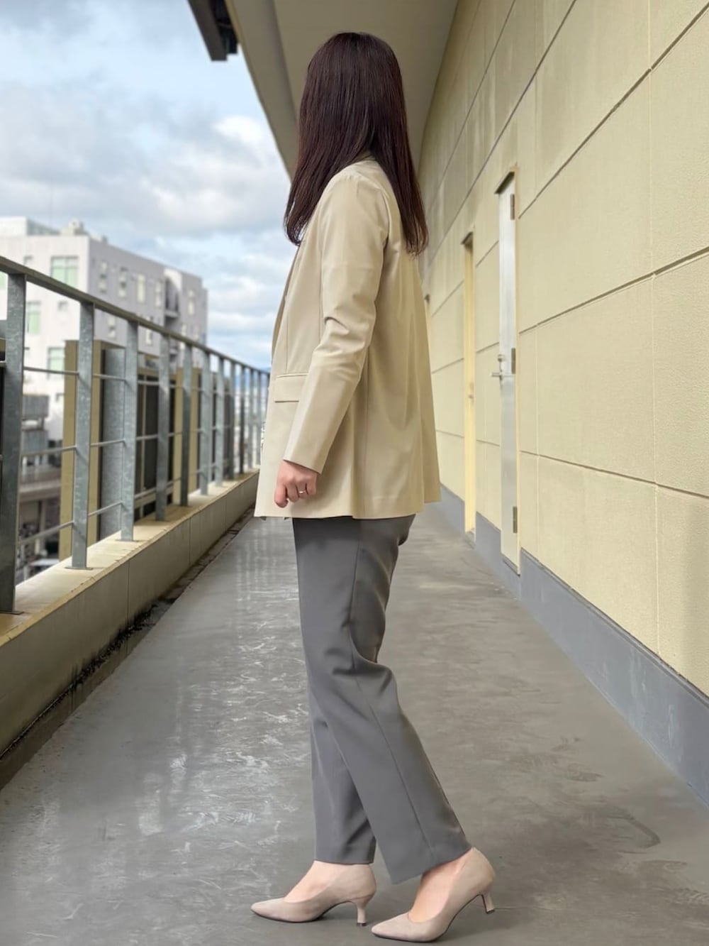 ベージュ系のスーツジャケット、ホワイト系のシャツ/ブラウス、グレー系のスーツパンツを着用したレディースの春コーディネートの2枚目の写真