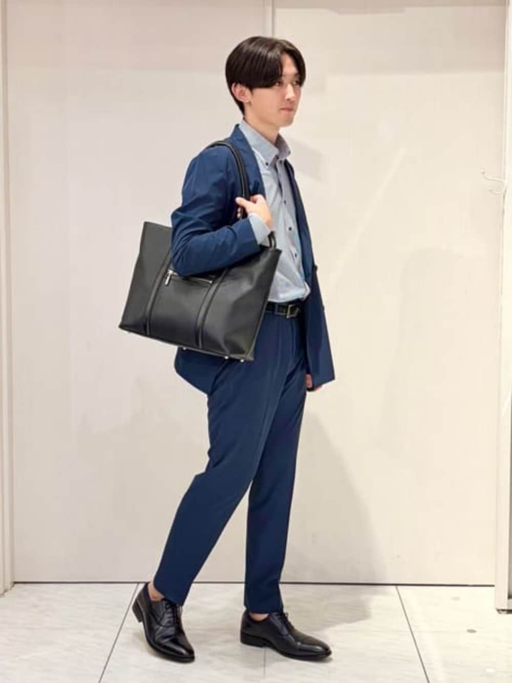 ブルー系のスーツセット、ブルー系のビジネスシャツ、ブラック系のビジネスバッグを着用したメンズの秋コーディネートの2枚目の写真