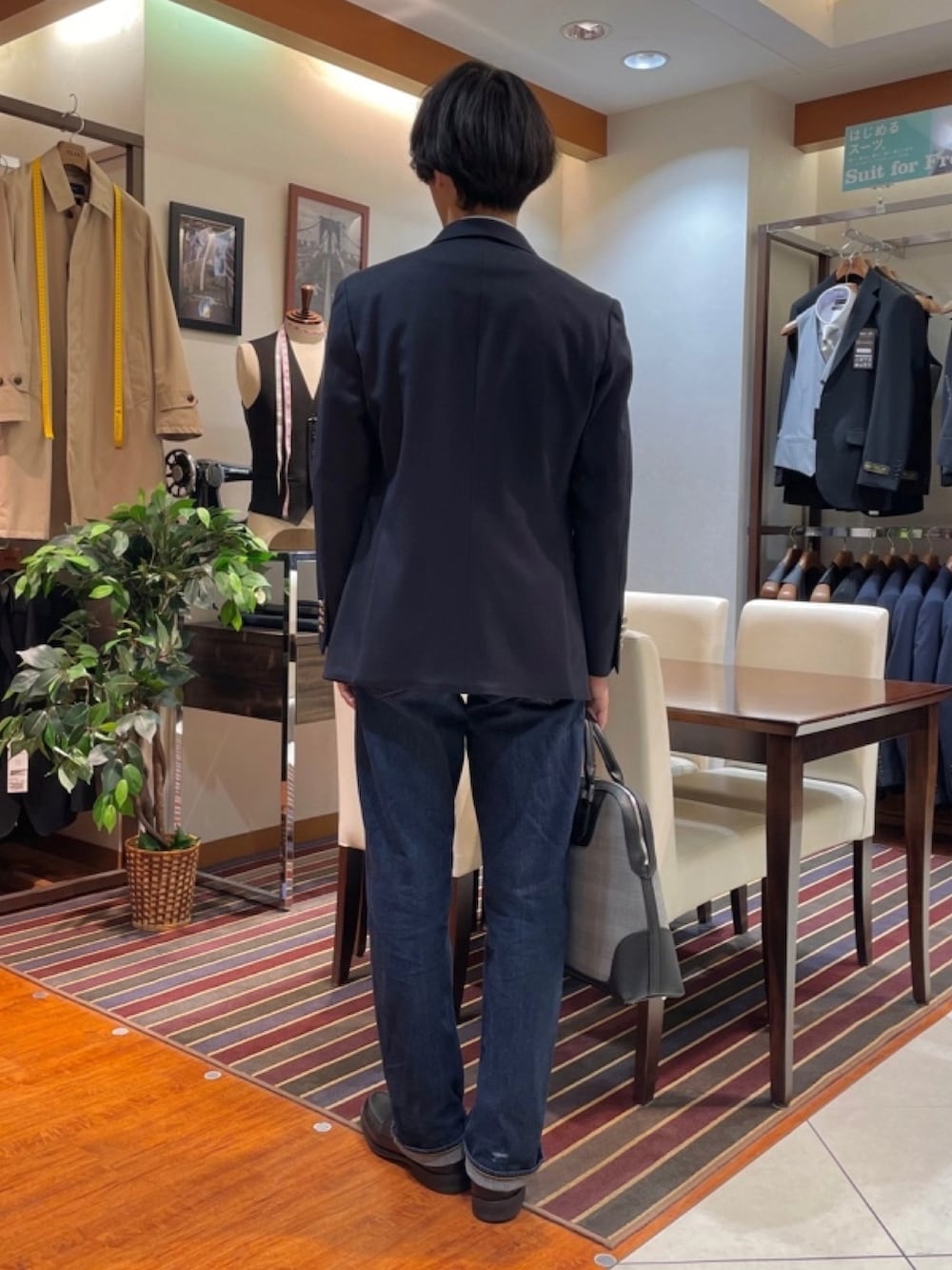 グレー系のビジネスバッグ、ブルー系のテーラードジャケット、ブルー系のビジネスシャツを着用したメンズの冬コーディネートの3枚目の写真