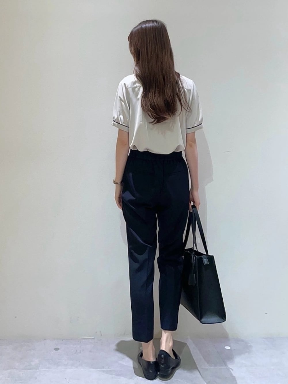 ベージュ系のシャツ/ブラウス、ブルー系のスラックス、ブラック系のトートバッグを着用したレディースの夏コーディネートの2枚目の写真