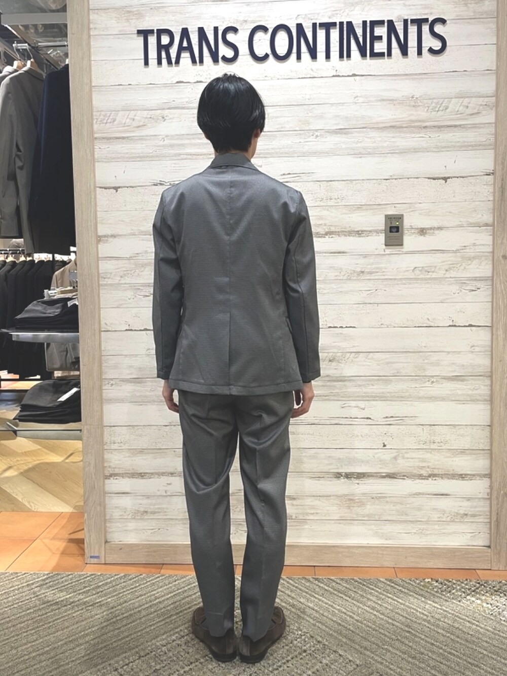 グレー系のテーラードジャケット、グレー系のスラックス、ブラック系のニット/セーターを着用したメンズの春コーディネートの2枚目の写真