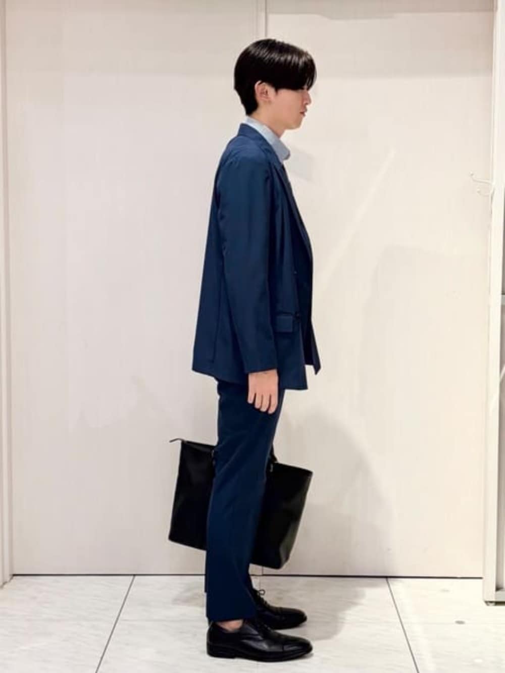 ブルー系のスーツセット、ブルー系のビジネスシャツ、ブラック系のビジネスバッグを着用したメンズの秋コーディネートの5枚目の写真