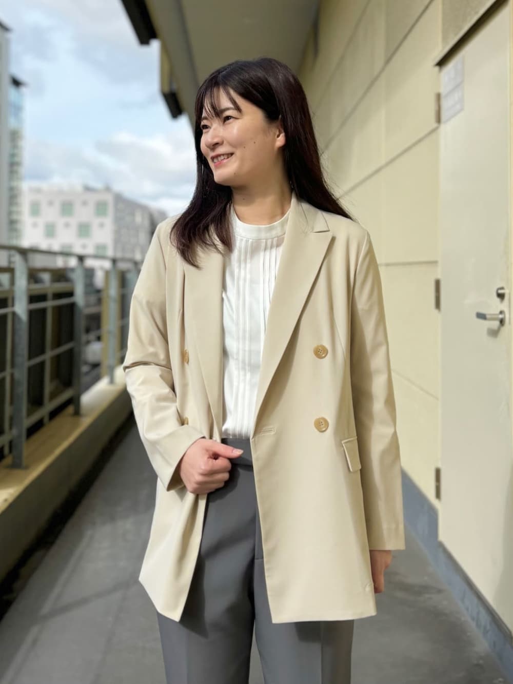 ベージュ系のスーツジャケット、ホワイト系のシャツ/ブラウス、グレー系のスーツパンツを着用したレディースの春コーディネートの3枚目の写真