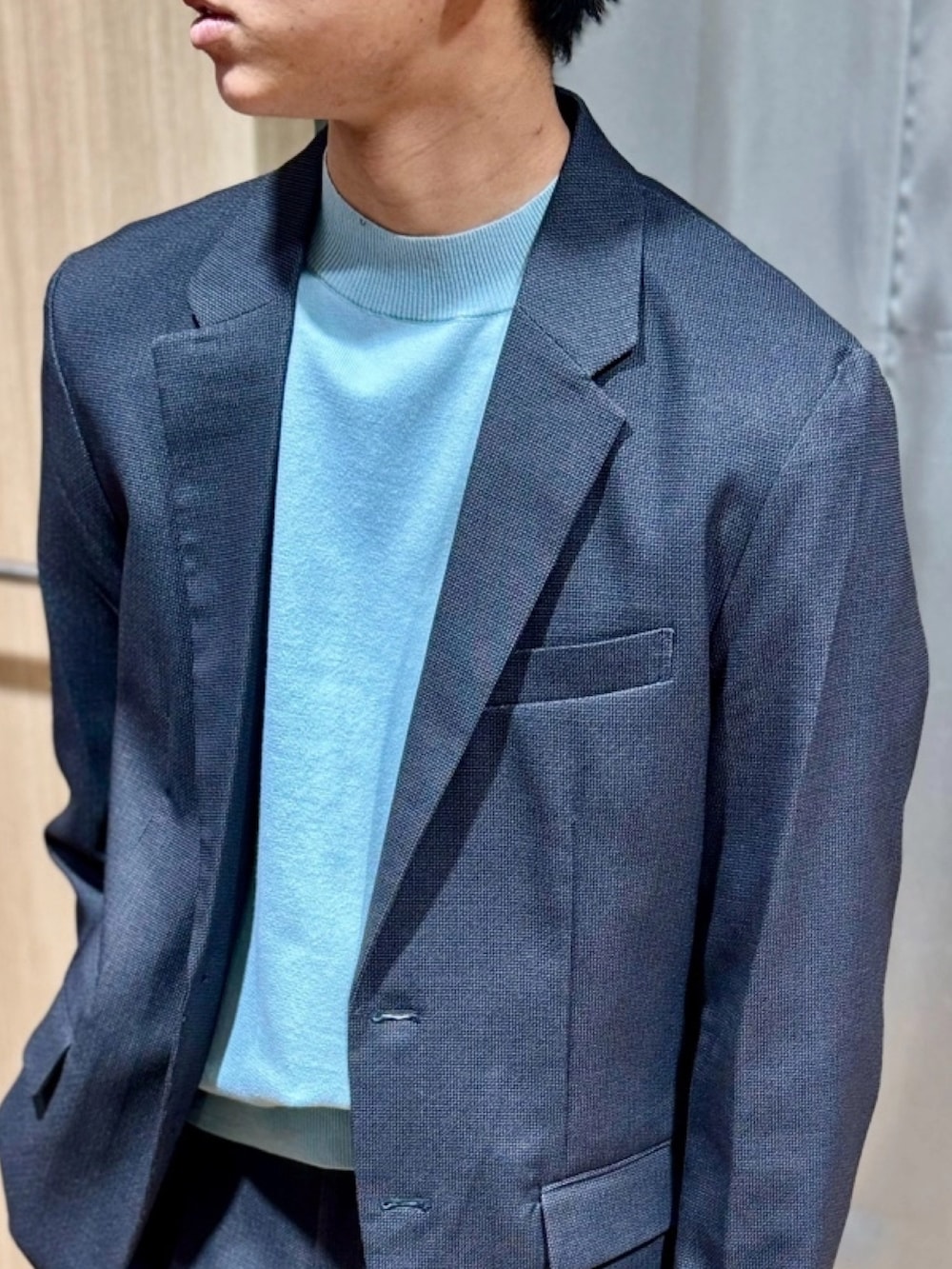 グレー系のテーラードジャケット、ブルー系のニット/セーター、グレー系のスラックスを着用したメンズの春コーディネートの2枚目の写真