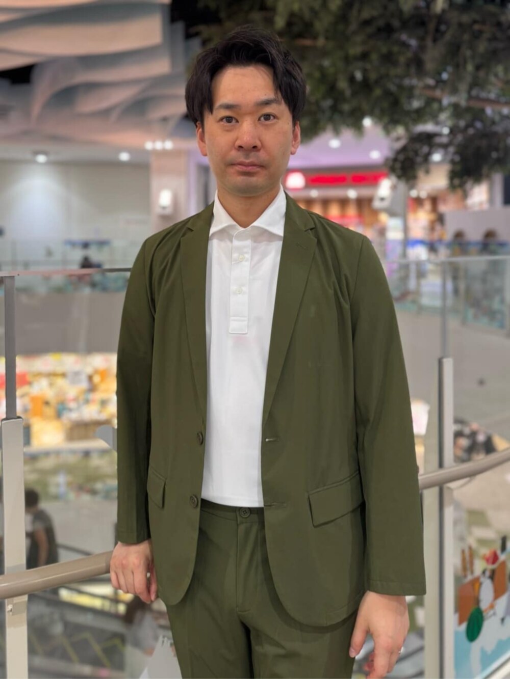 グリーン系のスーツセット、ホワイト系のポロシャツを着用したメンズの夏コーディネートの2枚目の写真