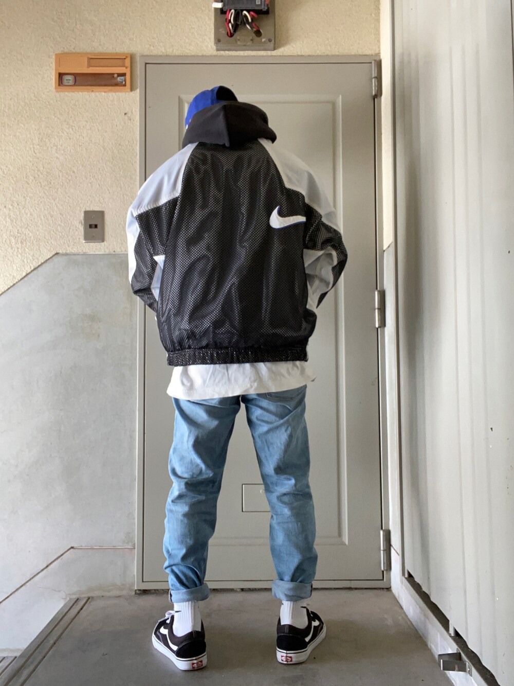 ホワイト系のナイロンジャケット、ブラック系のパーカー、ホワイト系のTシャツ/カットソーを着用したメンズの冬コーディネートの2枚目の写真