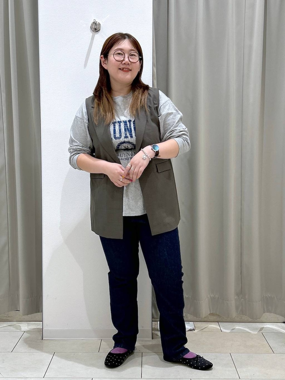 ブルー系のデニムパンツ、ブラック系のバレエシューズ、ブラウン系のベストを着用したレディースの秋コーディネートの3枚目の写真