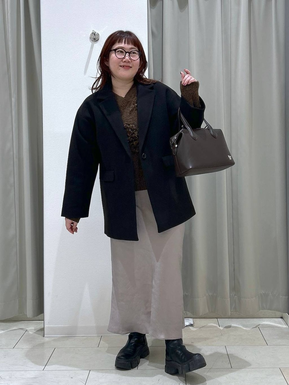 ブラック系のテーラードジャケット、グレー系のスカート、ブラウン系のショルダーバッグを着用したレディースの冬コーディネートの2枚目の写真