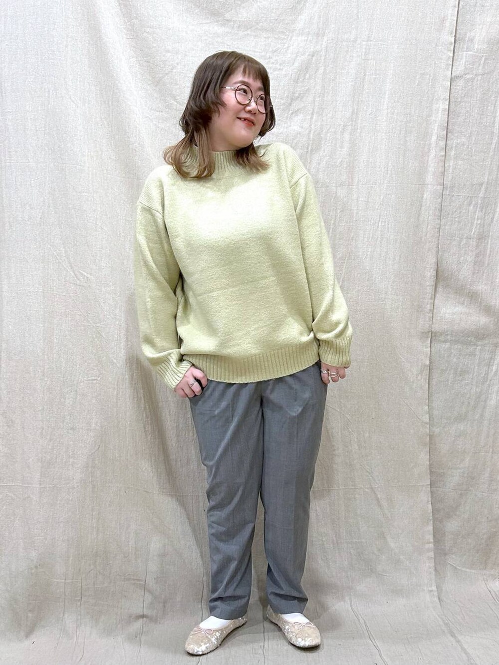 ブラウン系のノーカラーコート、グリーン系のニット/セーター、その他のその他パンツを着用したレディースの冬コーディネートの7枚目の写真