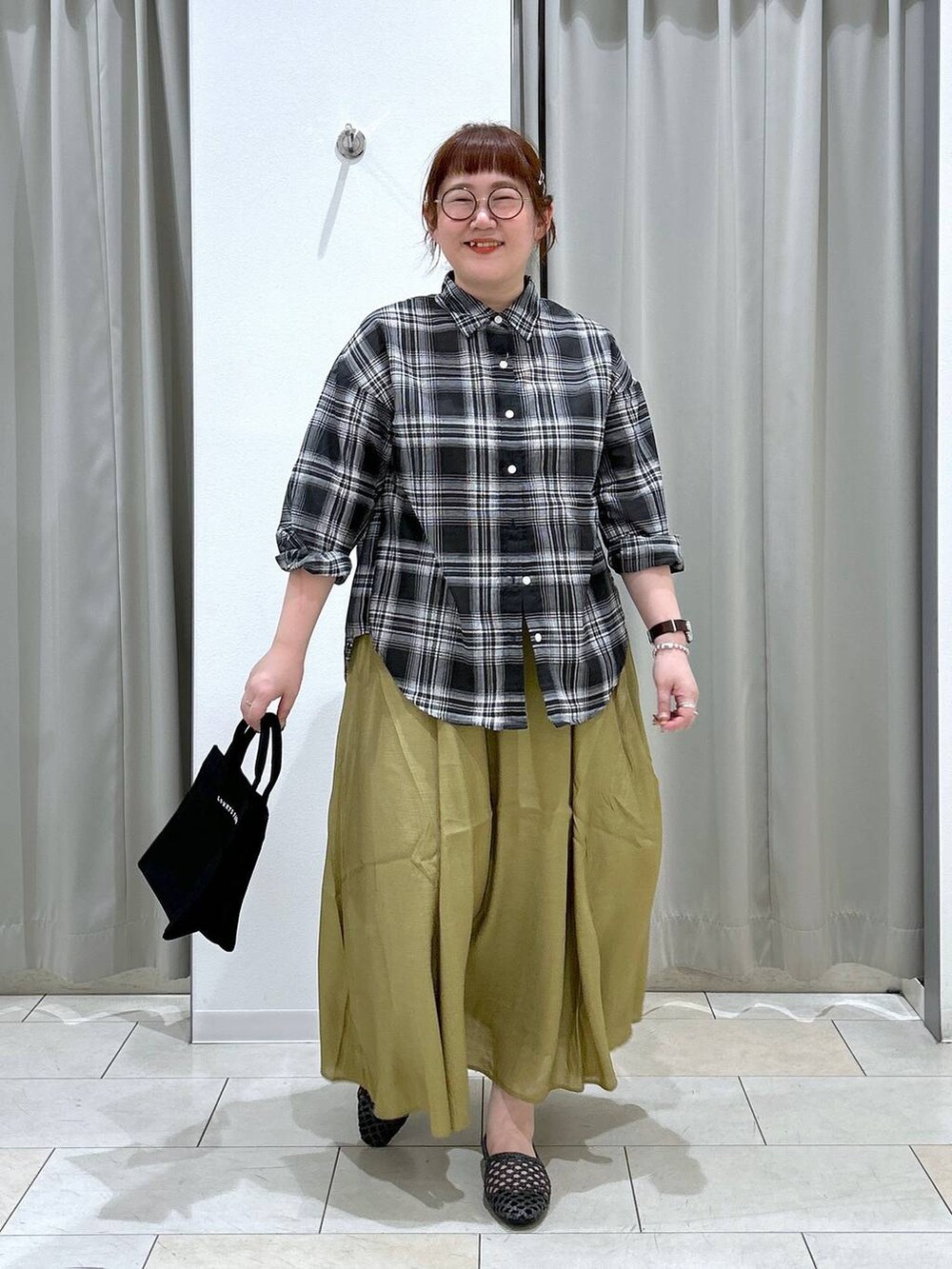 グリーン系のキャミソール、ブラック系のトートバッグ、イエロー系のスカートを着用したレディースの夏コーディネートの2枚目の写真