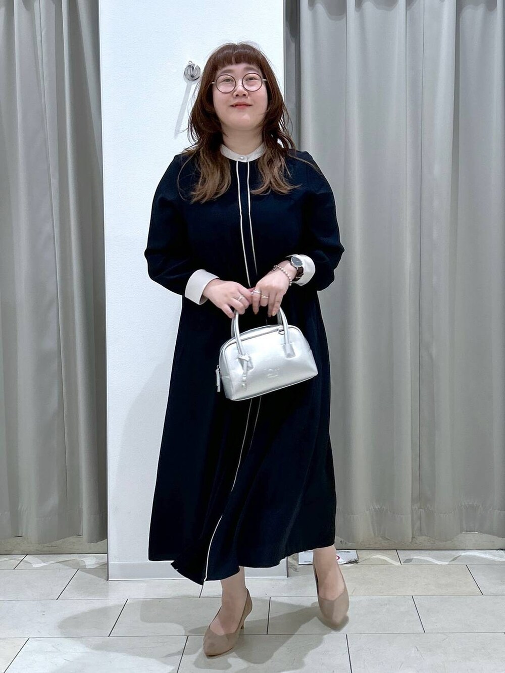 ブルー系のワンピース、ベージュ系のパンプス、シルバー系のボストンバッグを着用したレディースの秋コーディネートの3枚目の写真