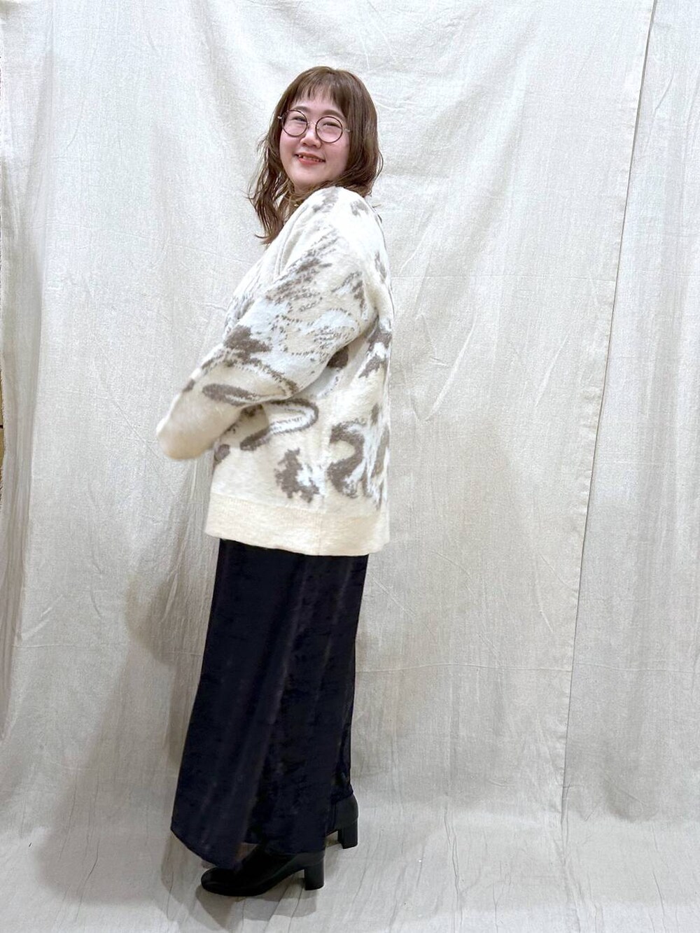 ブラック系のブーツ、ブラック系のスカート、ホワイト系のカーディガン/ボレロを着用したレディースの冬コーディネートの5枚目の写真