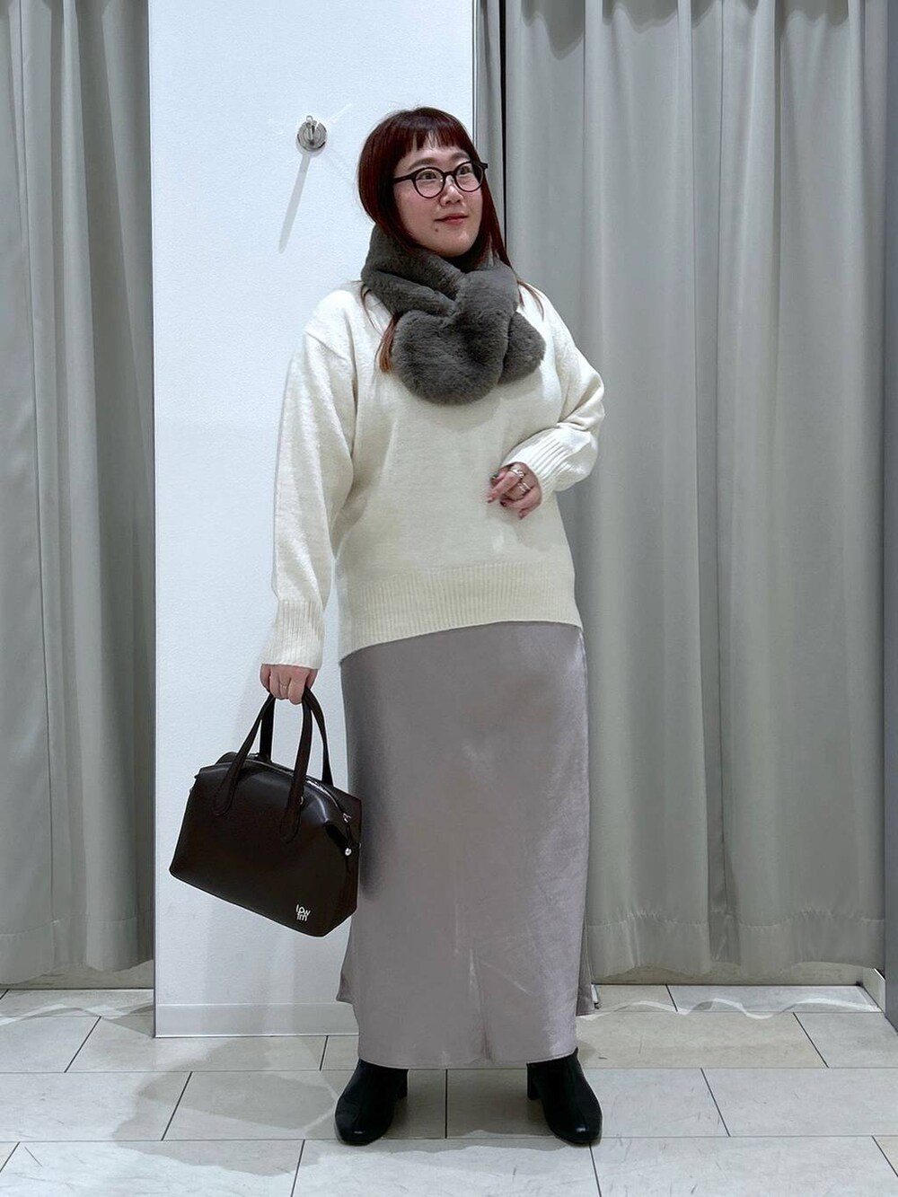 ホワイト系のニット/セーター、ブラック系のブーツ、ブラウン系のショルダーバッグを着用したレディースの冬コーディネートの2枚目の写真