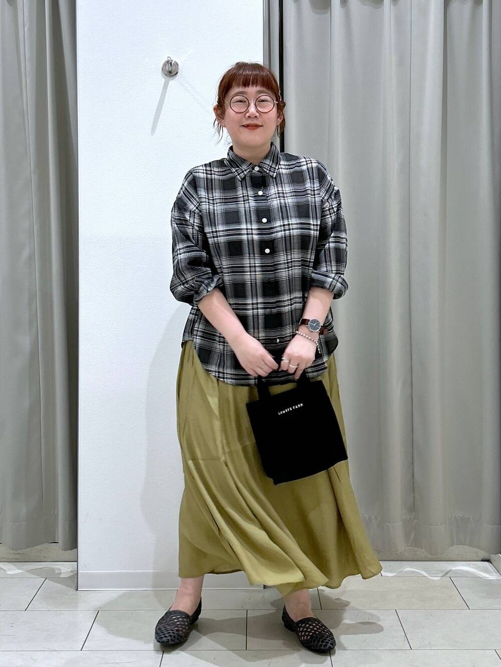 グリーン系のキャミソール、ブラック系のトートバッグ、イエロー系のスカートを着用したレディースの夏コーディネートの3枚目の写真