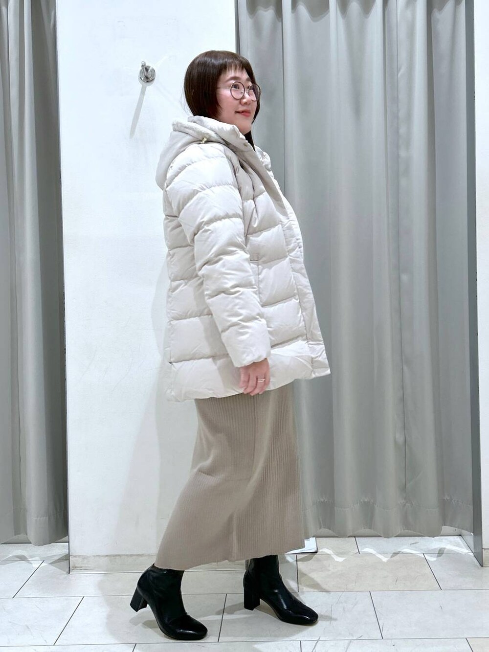 ベージュ系のダウンジャケット/コート、ブラック系のブーツ、ブラック系のボストンバッグを着用したレディースの冬コーディネートの6枚目の写真