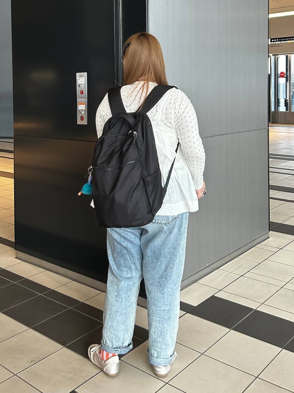 ブラック系のバックパック/リュック、ホワイト系のベスト、ブルー系のデニムパンツを着用したレディースの春コーディネートの4枚目の写真