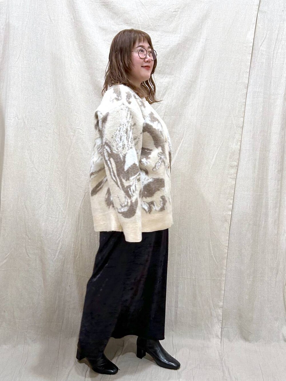 ブラック系のブーツ、ブラック系のスカート、ホワイト系のカーディガン/ボレロを着用したレディースの冬コーディネートの7枚目の写真