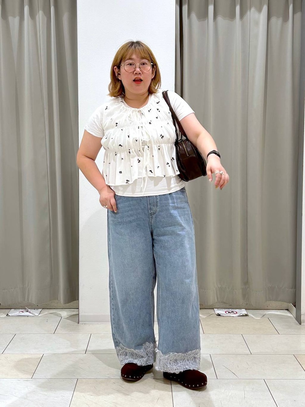 ブルー系のデニムパンツ、ブラウン系のボストンバッグ、ブラウン系のサンダルを着用したレディースの夏コーディネートの2枚目の写真