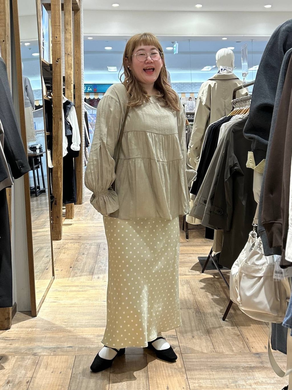 ベージュ系のスカート、ホワイト系のキャミソール、ブラック系のパンプスを着用したレディースの春コーディネートの2枚目の写真