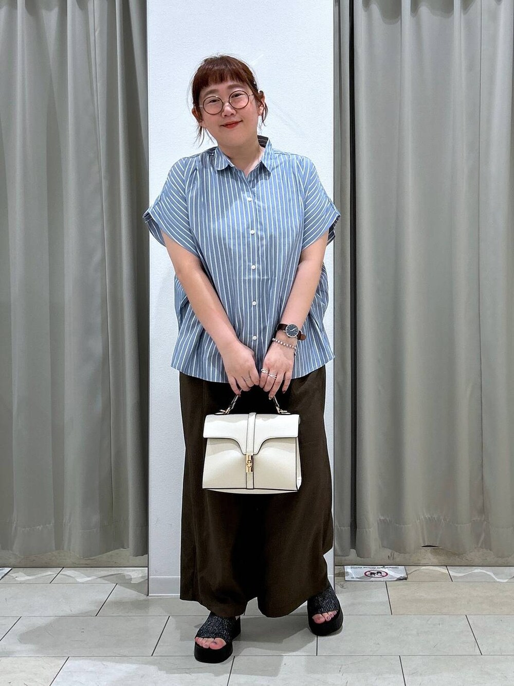 ブラック系のサンダル、ホワイト系のショルダーバッグ、ブラウン系のスラックスを着用したレディースの夏コーディネートの2枚目の写真