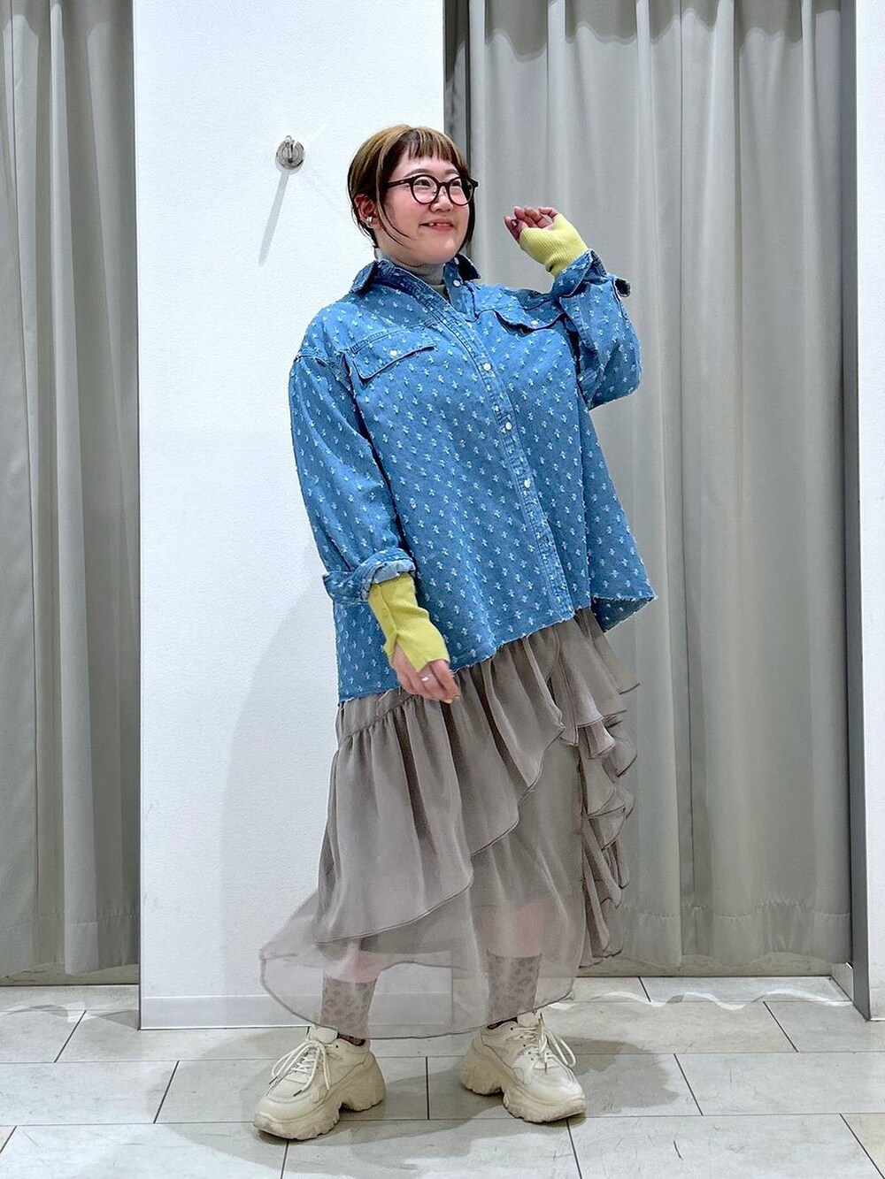 グレー系のニット/セーター、グレー系のスカート、ホワイト系のスニーカーを着用したレディースの冬コーディネートの2枚目の写真