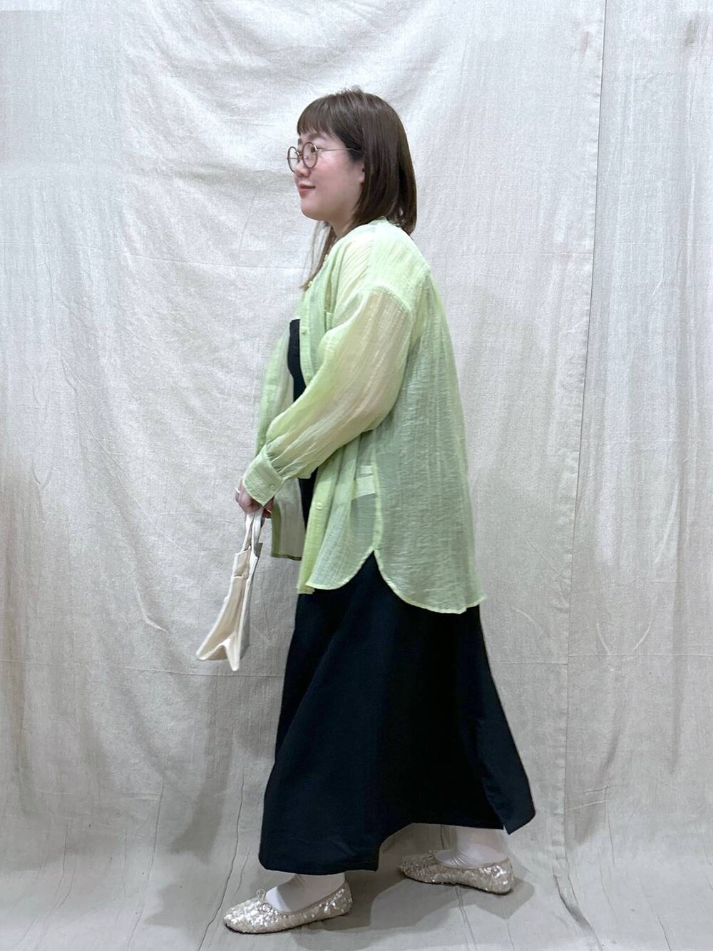 ホワイト系のタンクトップ、ブラック系のジャンパースカート、ホワイト系のバレエシューズを着用したレディースの春コーディネートの3枚目の写真