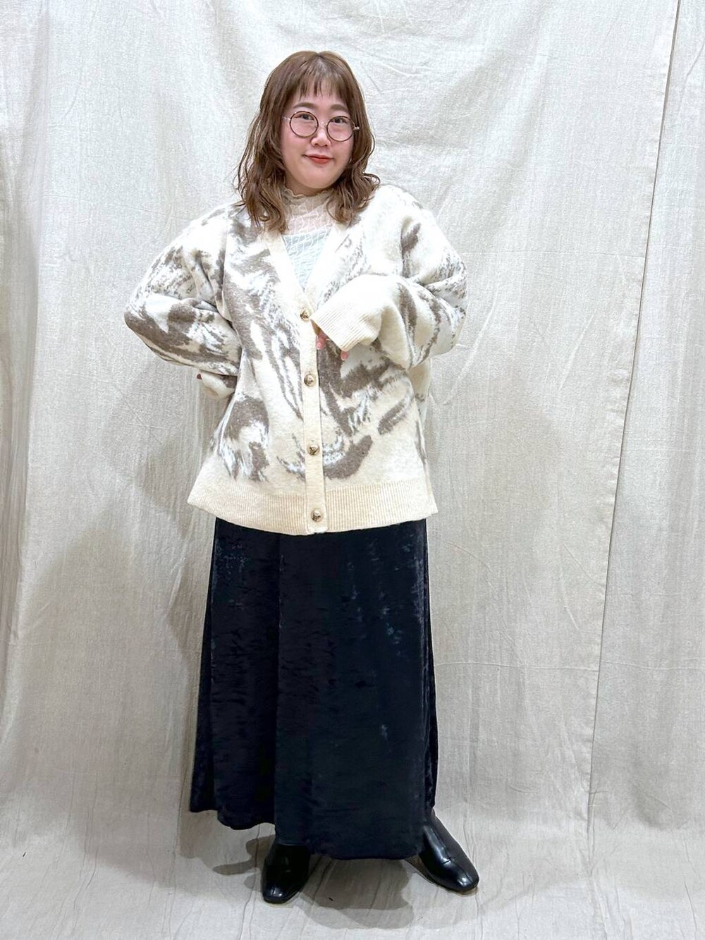 ブラック系のブーツ、ブラック系のスカート、ホワイト系のカーディガン/ボレロを着用したレディースの冬コーディネートの4枚目の写真