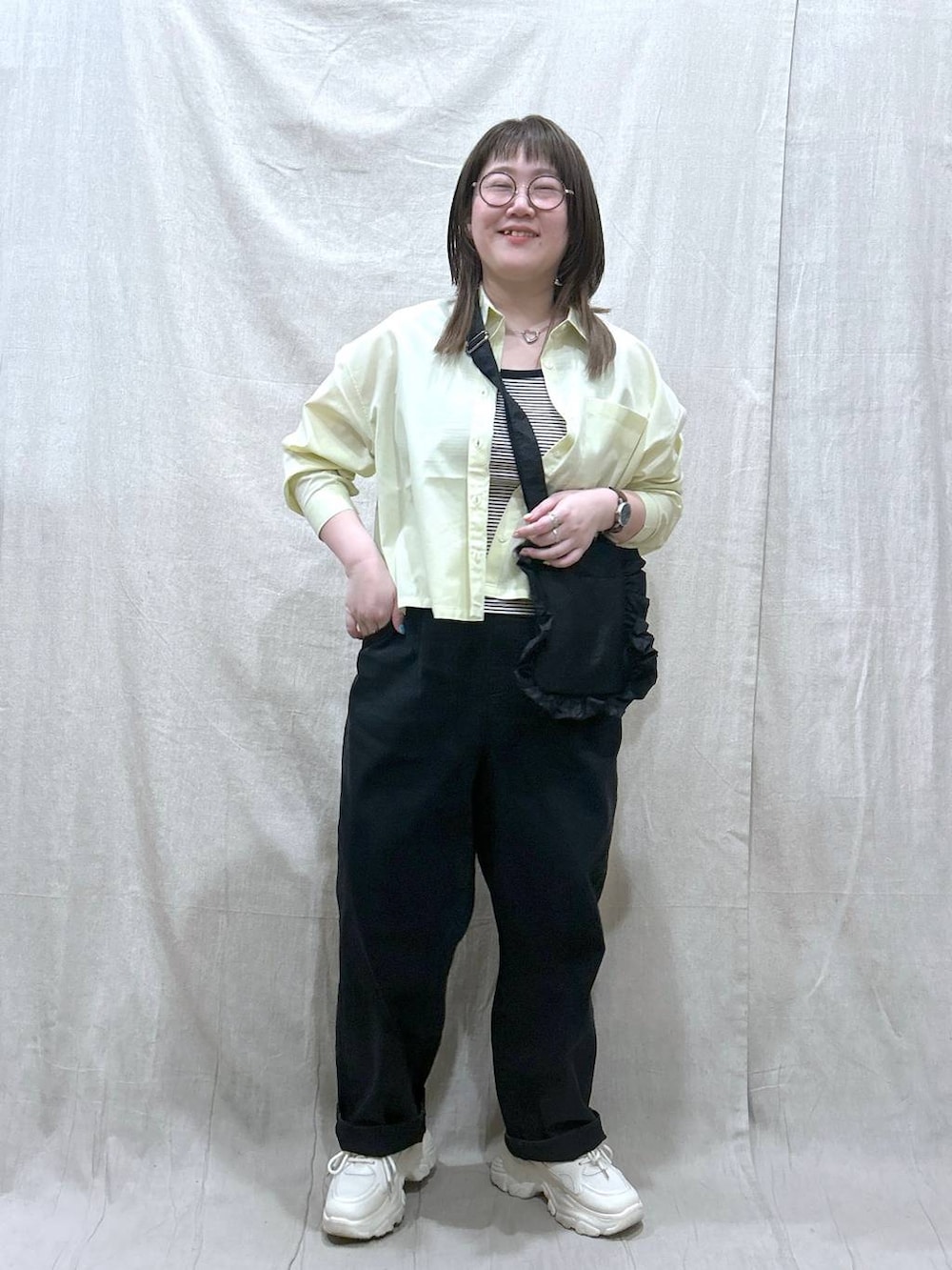 ブラック系のタンクトップ、ブラック系のデニムパンツ、イエロー系のシャツ/ブラウスを着用したレディースの春コーディネートの2枚目の写真