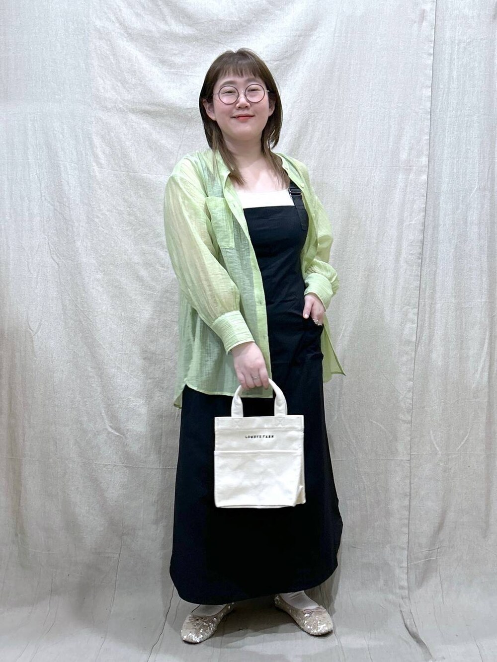 ホワイト系のタンクトップ、ブラック系のジャンパースカート、ホワイト系のバレエシューズを着用したレディースの春コーディネートの2枚目の写真