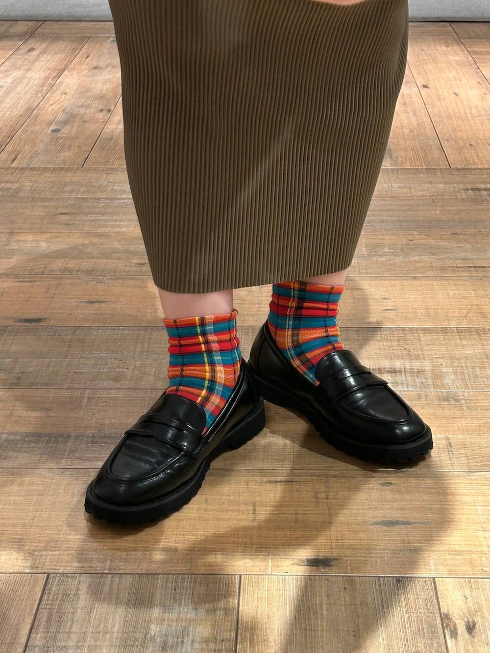 ブラック系のローファー、グリーン系のスカート、ホワイト系のタンクトップを着用したレディースの秋コーディネートの2枚目の写真