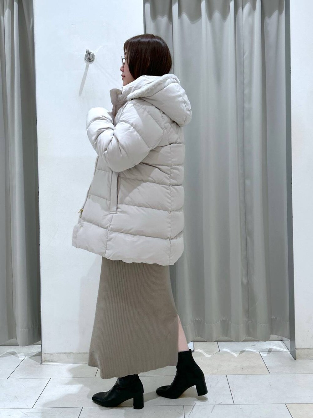 ベージュ系のダウンジャケット/コート、ブラック系のブーツ、ブラック系のボストンバッグを着用したレディースの冬コーディネートの5枚目の写真