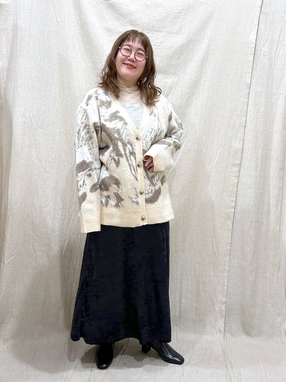 ブラック系のブーツ、ブラック系のスカート、ホワイト系のカーディガン/ボレロを着用したレディースの冬コーディネートの2枚目の写真