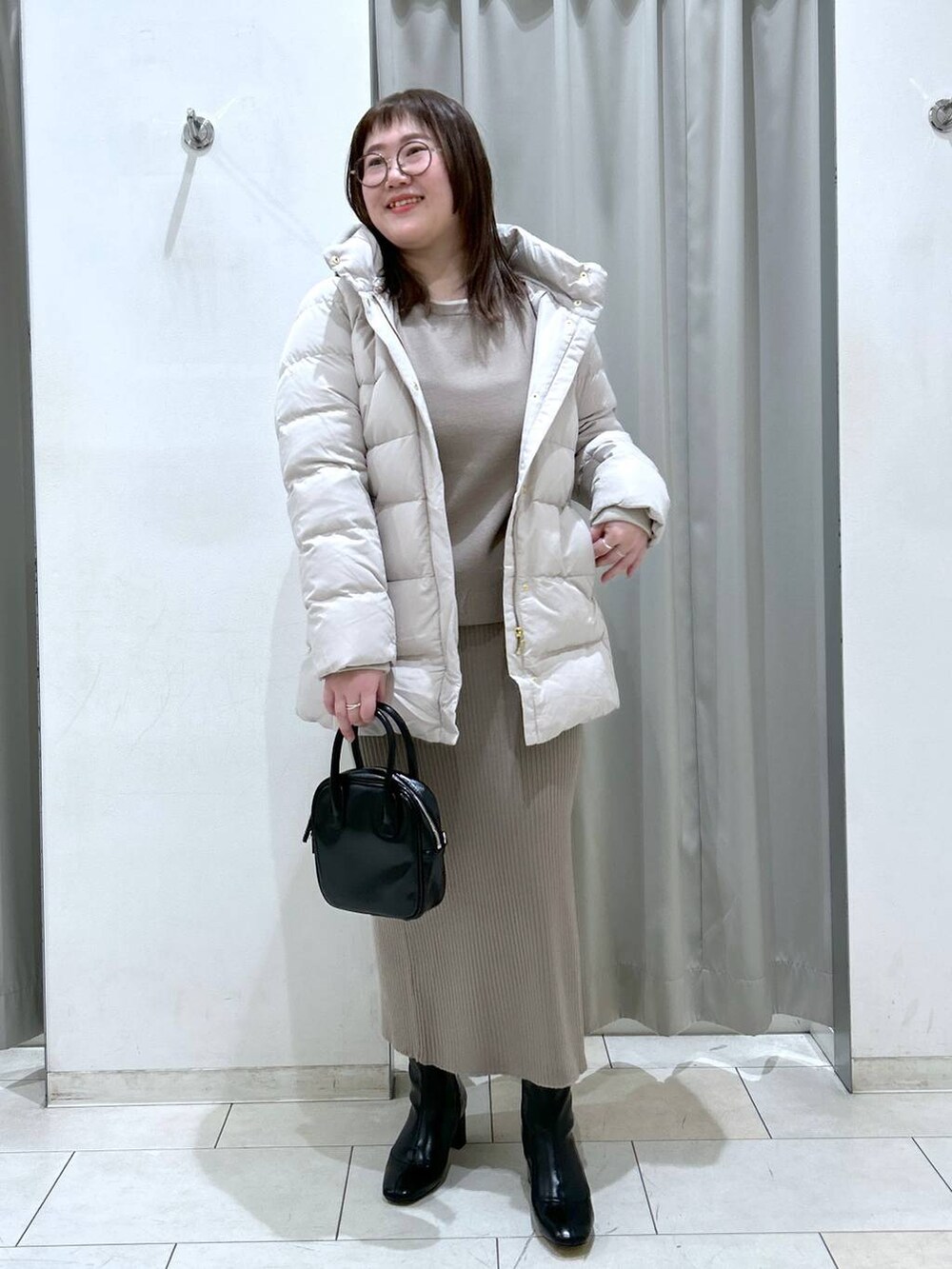 ベージュ系のダウンジャケット/コート、ブラック系のブーツ、ブラック系のボストンバッグを着用したレディースの冬コーディネートの3枚目の写真