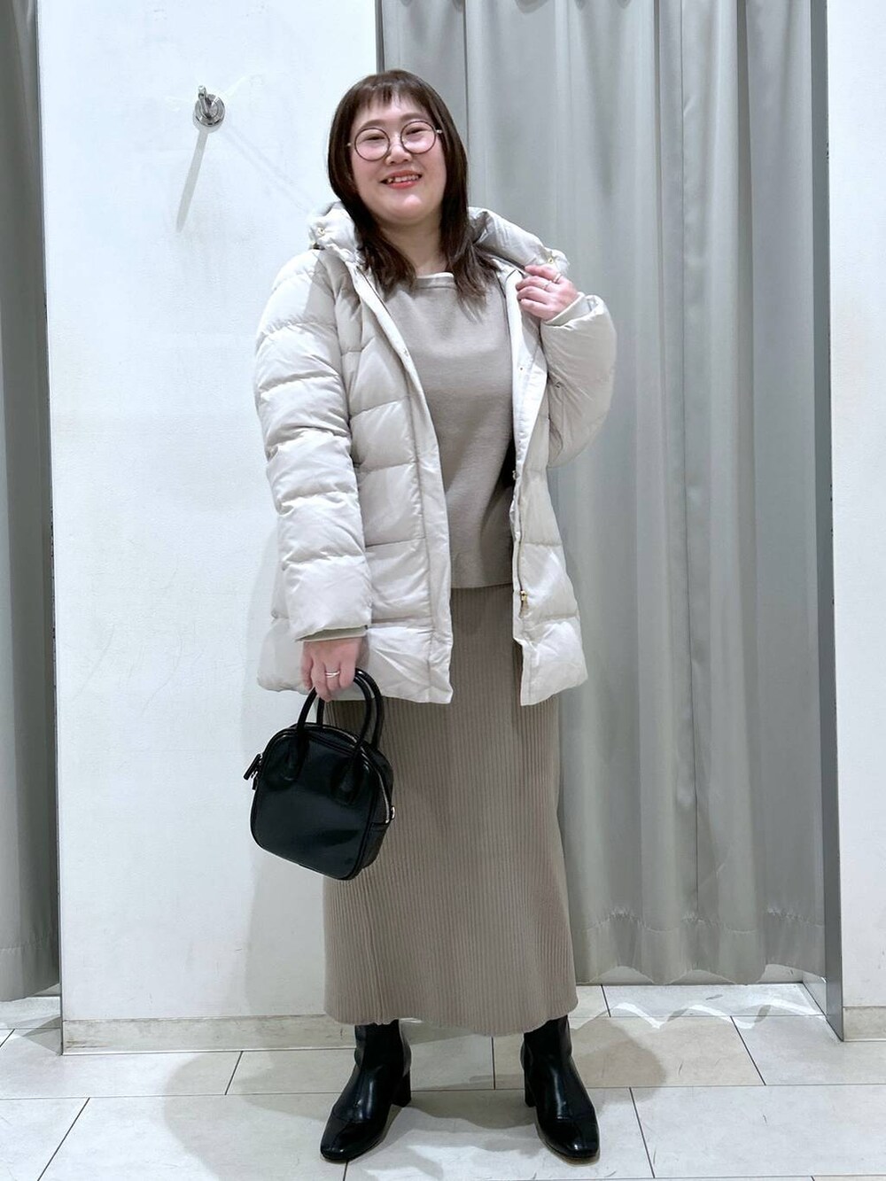 ベージュ系のダウンジャケット/コート、ブラック系のブーツ、ブラック系のボストンバッグを着用したレディースの冬コーディネートの2枚目の写真