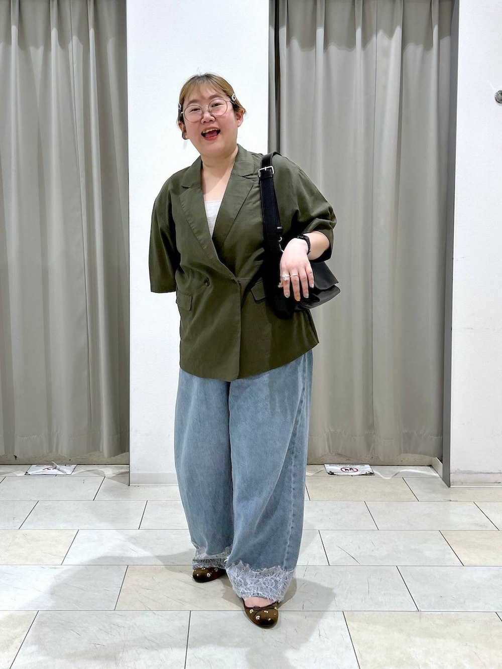 ブルー系のデニムパンツ、ブラック系のショルダーバッグ、ブラウン系のバレエシューズを着用したレディースの夏コーディネートの3枚目の写真