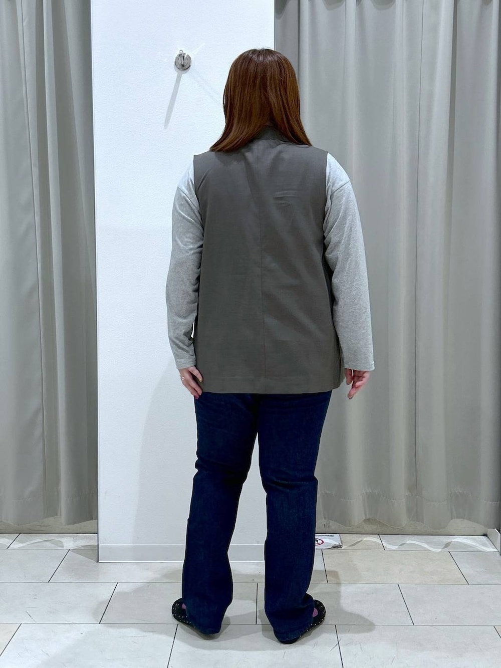 ブルー系のデニムパンツ、ブラック系のバレエシューズ、ブラウン系のベストを着用したレディースの秋コーディネートの5枚目の写真