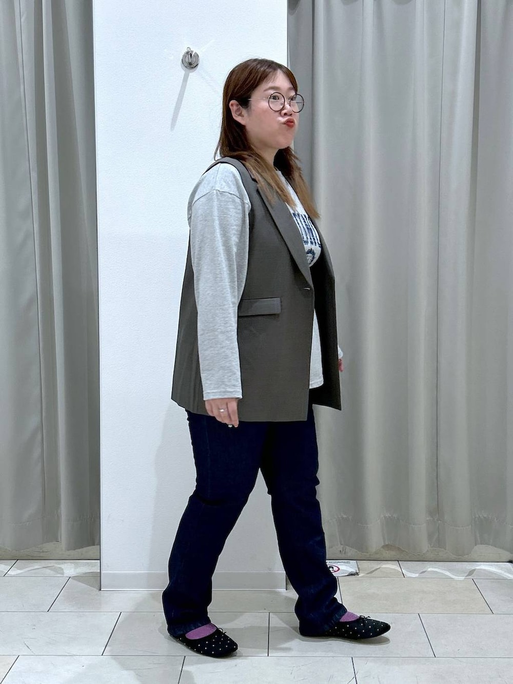 ブルー系のデニムパンツ、ブラック系のバレエシューズ、ブラウン系のベストを着用したレディースの秋コーディネートの6枚目の写真