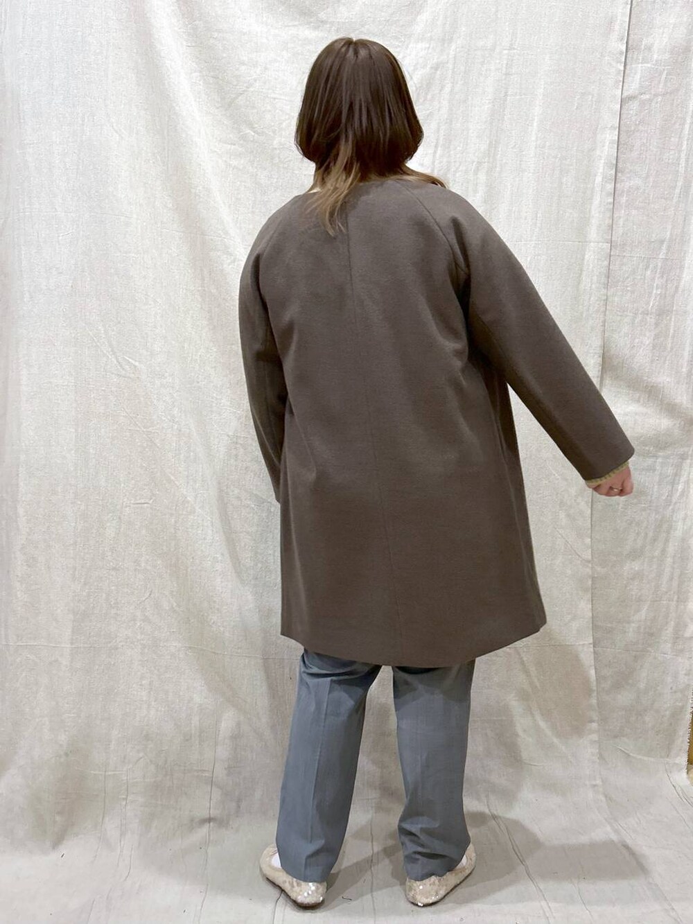 ブラウン系のノーカラーコート、グリーン系のニット/セーター、その他のその他パンツを着用したレディースの冬コーディネートの5枚目の写真